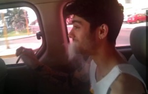 Louis Tomlinson smoking an illegal substance. Screenshot from video on MailOnline.