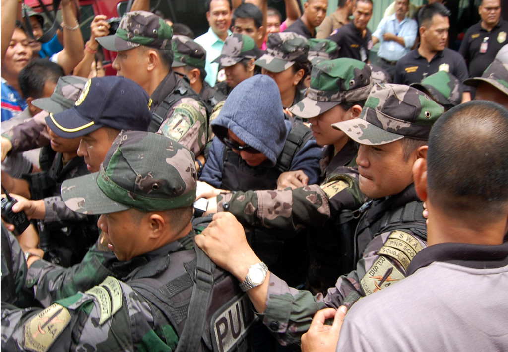 Alleged pork barrel scam mastermind Janet Lim-Napoles (center in right photo) is escorted by Philippine National Police (PNP) personnel out of the courtroom after her arraignment for plunder charges on Thursday (June 26, 2014) at the Sandiganbayan in Quezon City. (PNA photos by Gil S. Calinga)