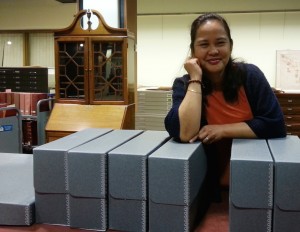 Mary Grace Golfo rests on some Hollinger boxes in Archives and Special Collections. 