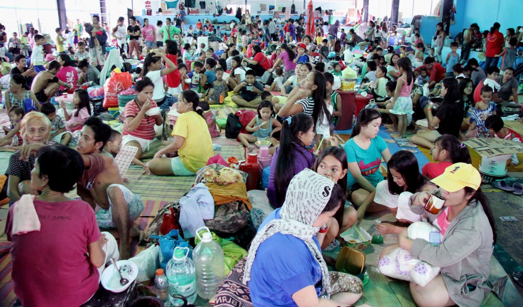 Volunteers assist more than 5,000 evacuees who are still housed at a covered court in Barangay Silangan, Quezon City. As of 9:15 a.m. Saturday, records show that at least 5,688 residents remain in said evacuation center. Thousands of other residents are said to have returned to their homes as the weather improves. (PNA photo by Oliver Marquez)