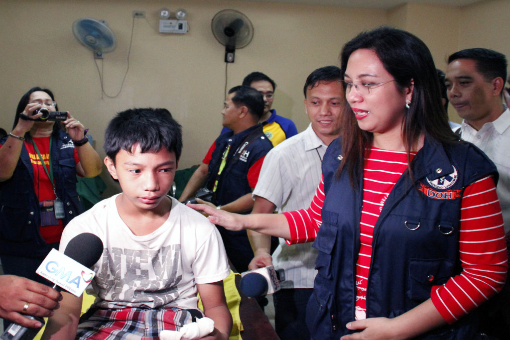 Department of Health (DOH) Acting Secretary Janette L. Garin comforts 13-year-old Justin Garcia who is confined at the Philippine Orthopedic Center (POC) in Quezon City after he was injured in a piccolo firecracker explosion. Dr. Garin visited the POC on New Year's Eve Wednesday (Dec. 31, 2014). (PNA photo by Joey O. Razon)