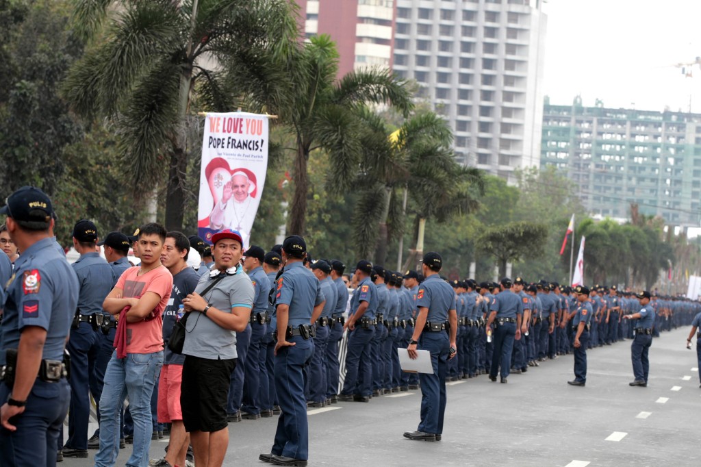A huge crowd faces a long barrier of policemen as they patiently wait for the motorcade of Pope Francis to pass by along Roxas Boulevard, Manila on Thursday (January 15, 2015). (PNA photo by Jess M. Escaros Jr.)