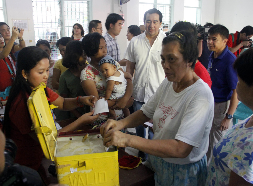 A woman casts her votes as Commission on Elections Chairman Andres Bautista looks on during mock elections held at Bacoor National High School Annex in Poblacion, Bacoor, Cavite.  (Photo by Avito Dalan/PNA)