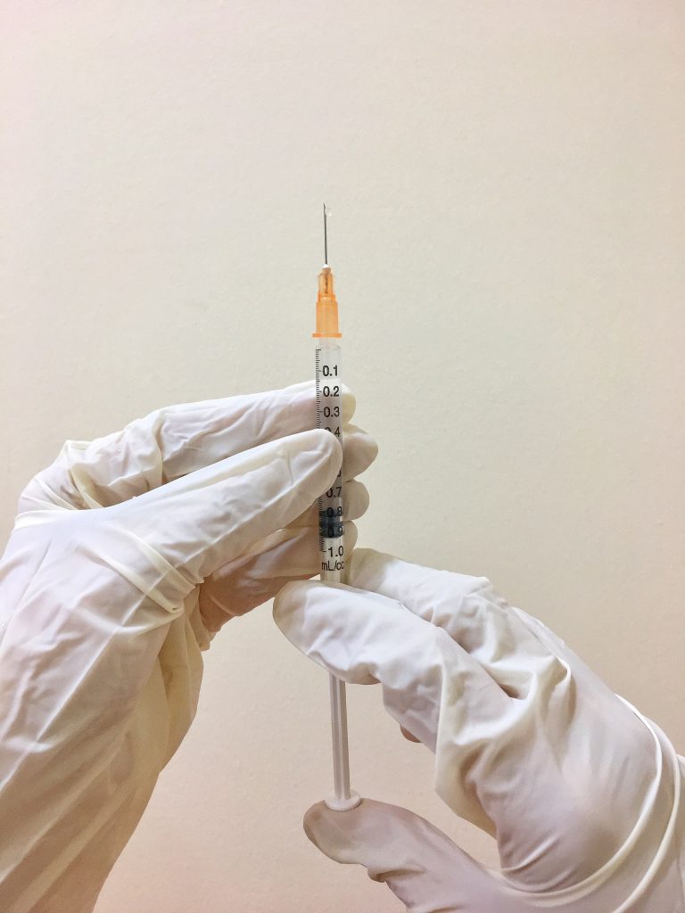 Two gloved hands preparing an injection