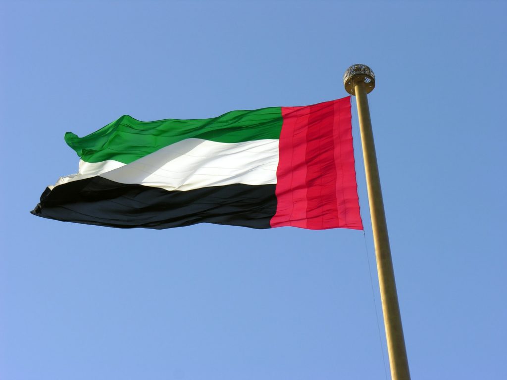 Flag of UAE on a pole across a blue sky background