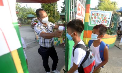A personnel checking students' temperature before they enter the school
