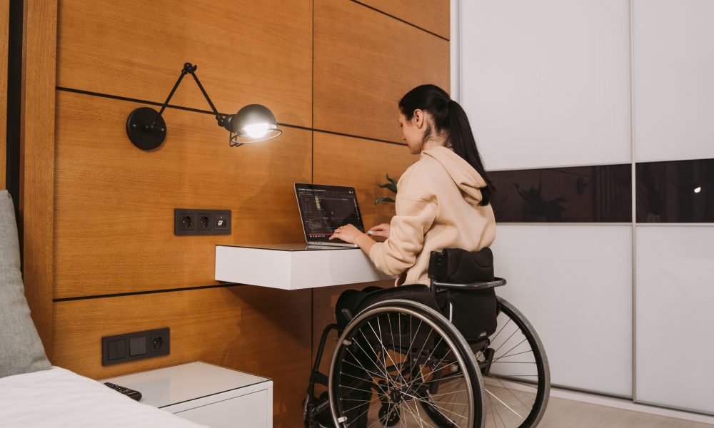 A woman sitting on her wheelchair while typing on a laptop