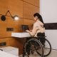 A woman sitting on her wheelchair while typing on a laptop