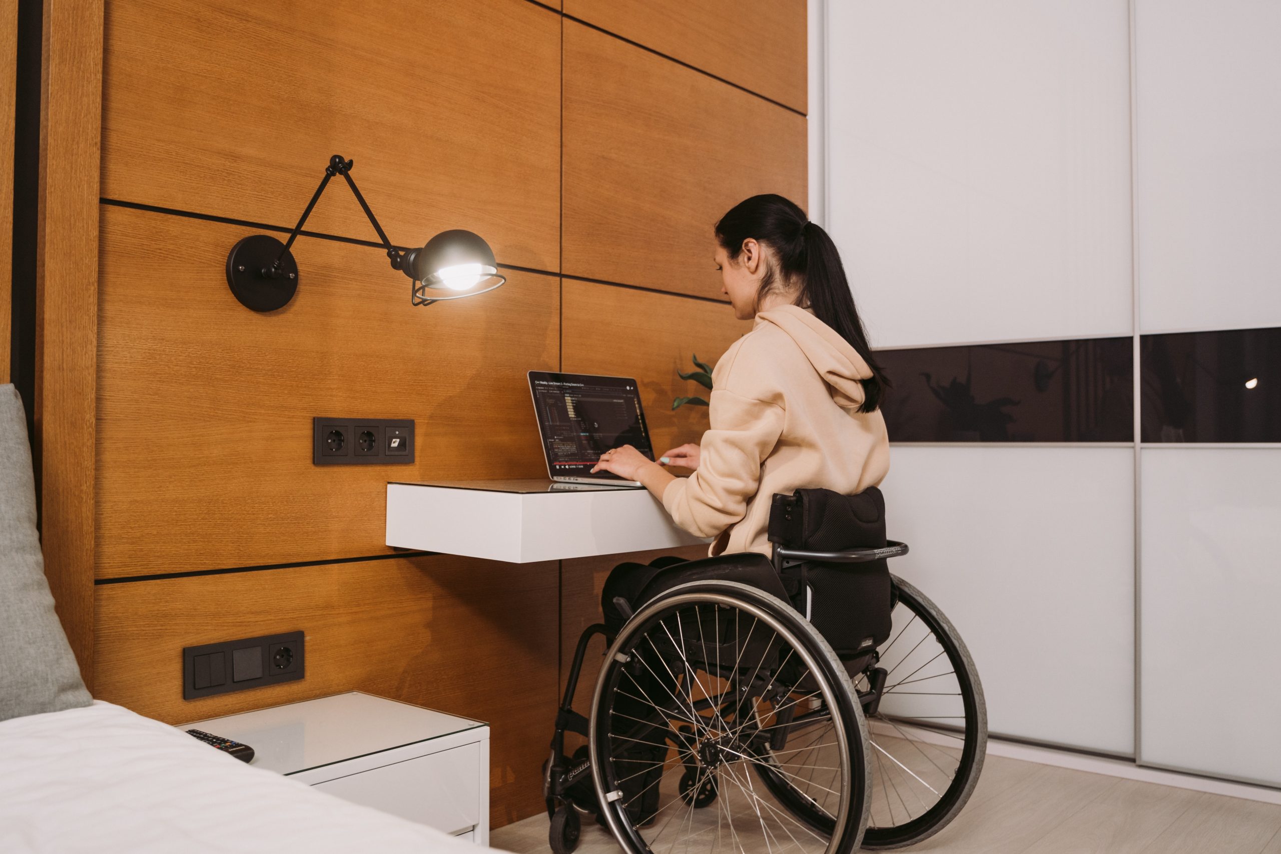 A woman sitting on her wheelchair while typing on a laptop