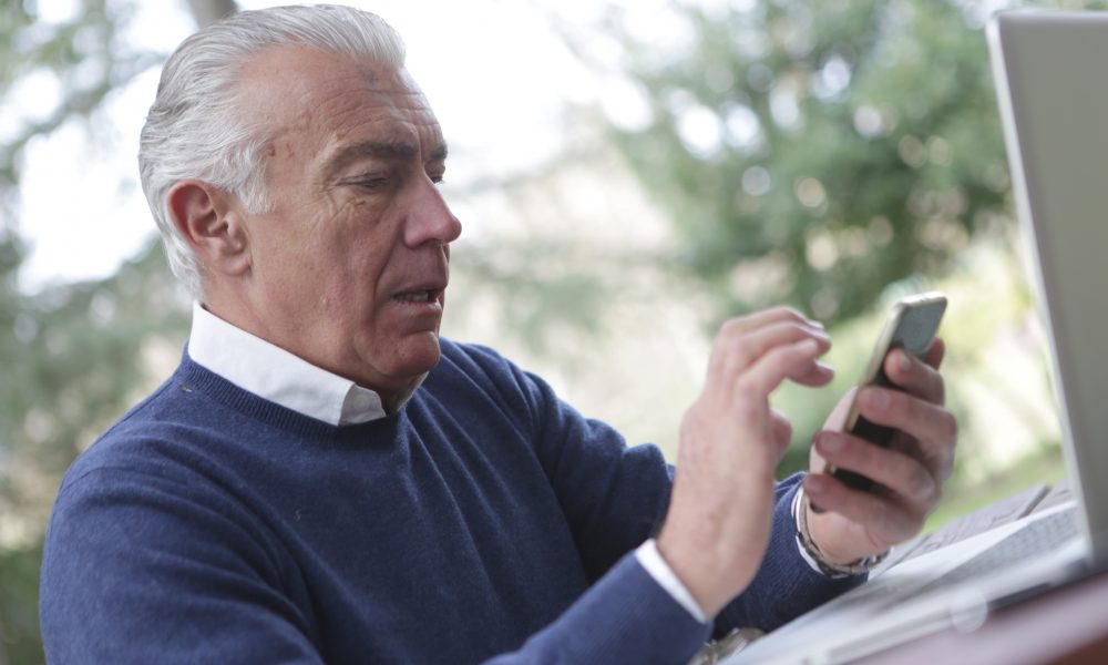 Man in blue sweater holding a smartphone