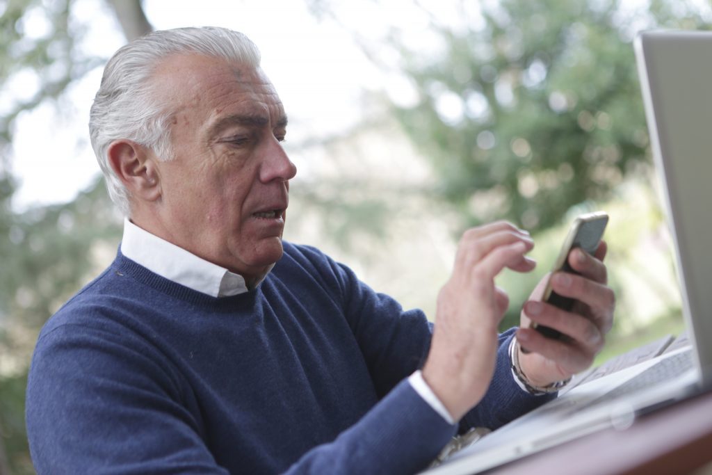 Man in blue sweater holding a smartphone
