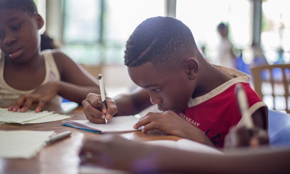 black kid writing on paper