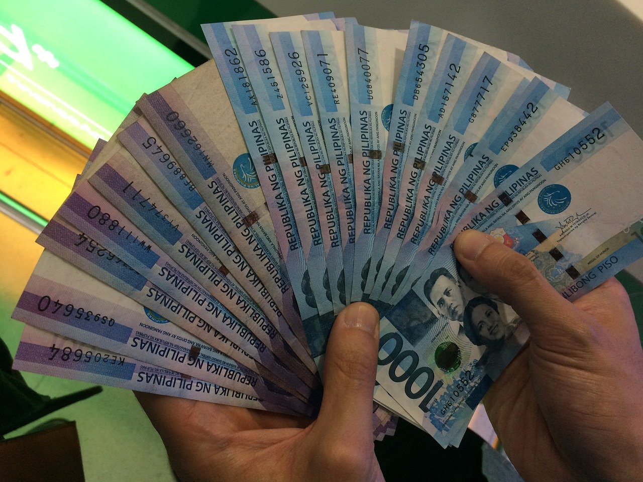 hands holding one-thousand peso bills