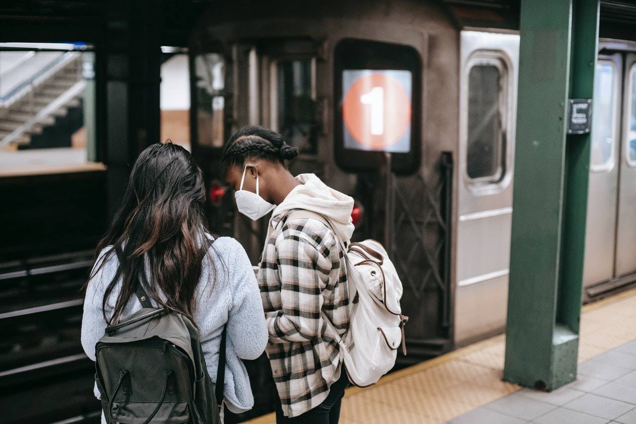 2 girls wearing mask while waiting for train