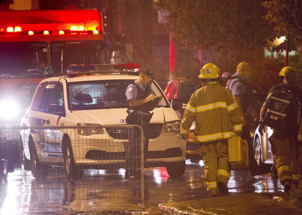 Police and firefighters work at the rear of an auditorium where a gunman shot and killed at least one person during the Parti Québécois victory rally