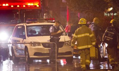 Police and firefighters work at the rear of an auditorium where a gunman shot and killed at least one person during the Parti Québécois victory rally