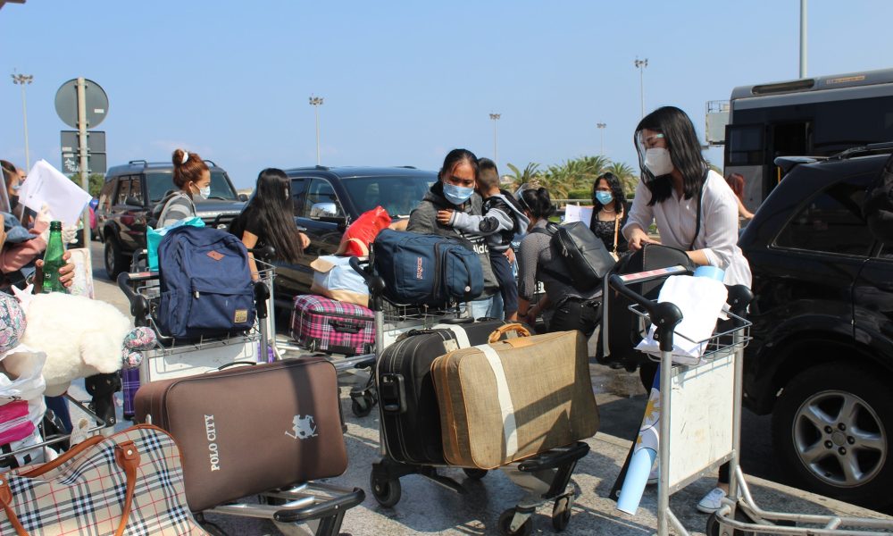 Filipino women wearing facemasks with their luggage