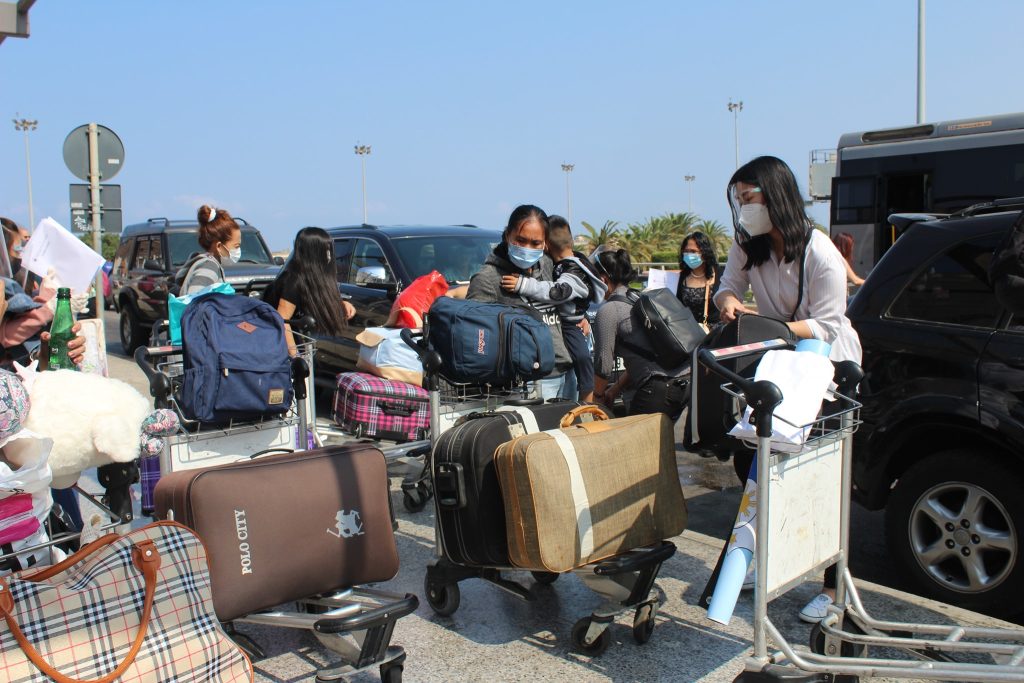 Filipino women wearing facemasks with their luggage