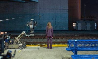 Woman on her back facing a train rail, with cameras on set