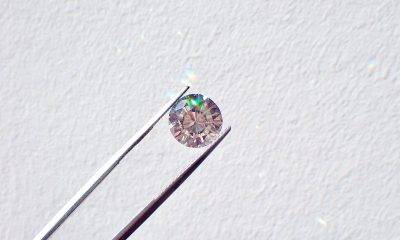 Diamond held between tweezers on a white wall