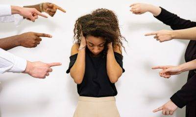Fingers pointing at a woman who is covering her ears
