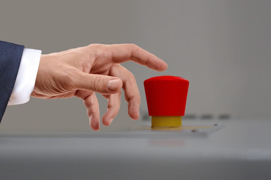 Hand about to press a red button