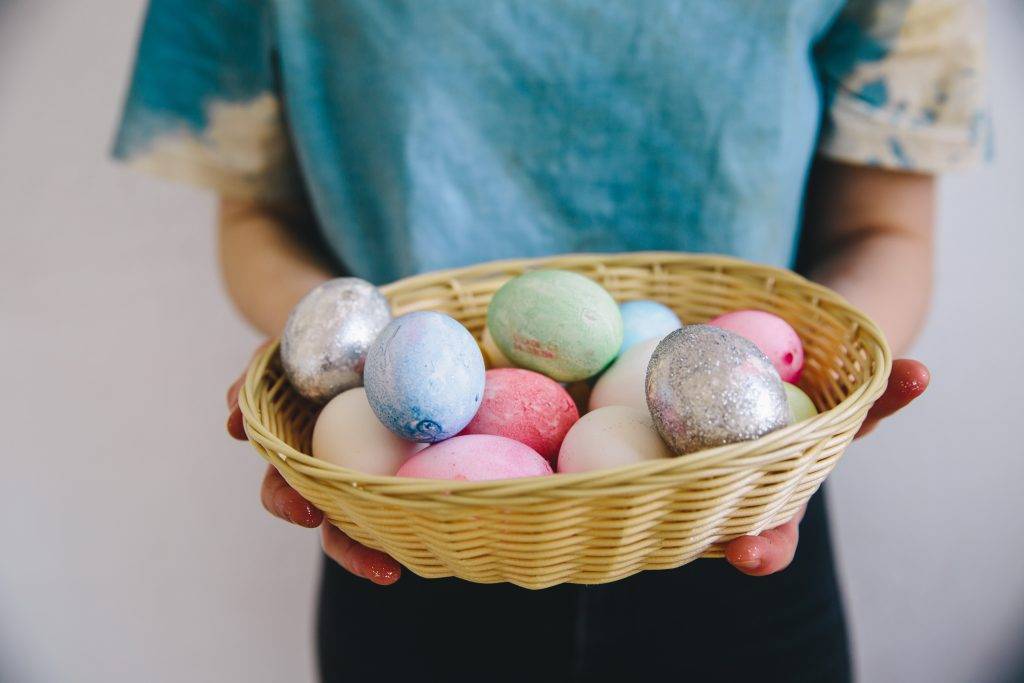 Person holding a basket of colorful eggs