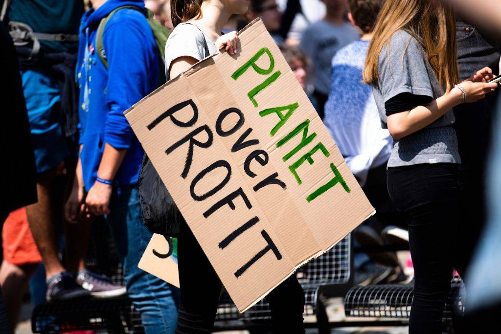 Woman holding Planet over Profit placard