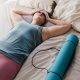 Woman lying in bed with yoga mat beside her