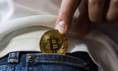 person putting gold bitcoin in pocket