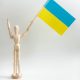 wooden figurine holding a ukrainian flag