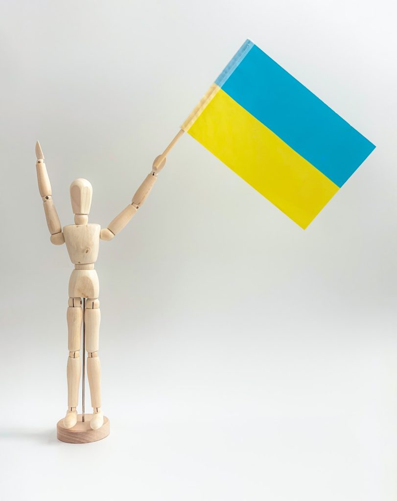 wooden figurine holding a ukrainian flag