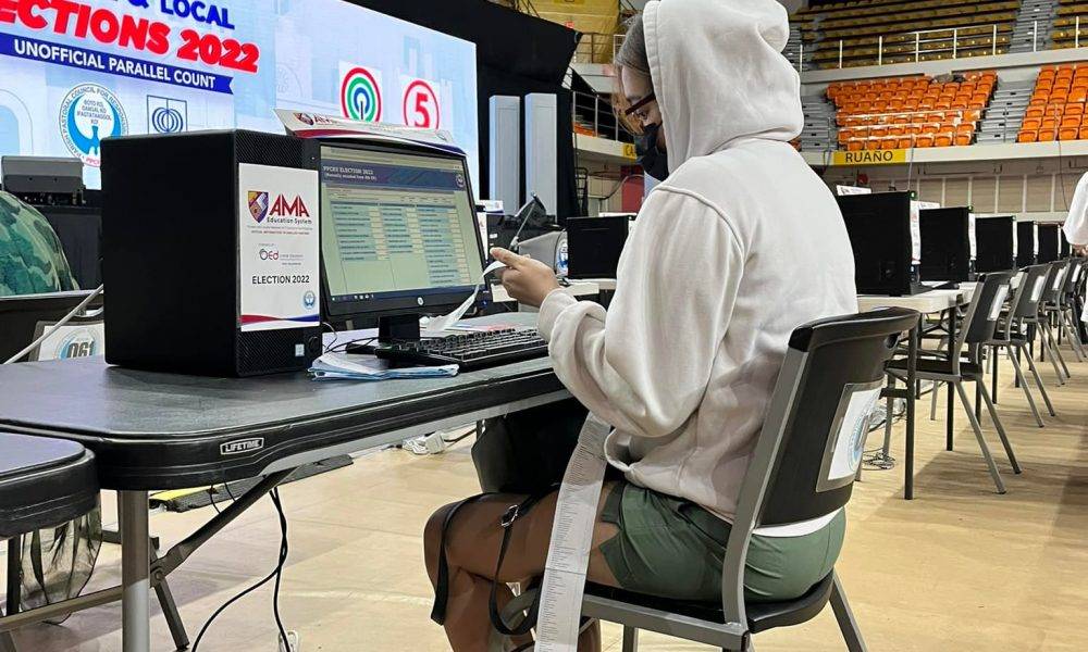 Person in a white hood in front of a computer