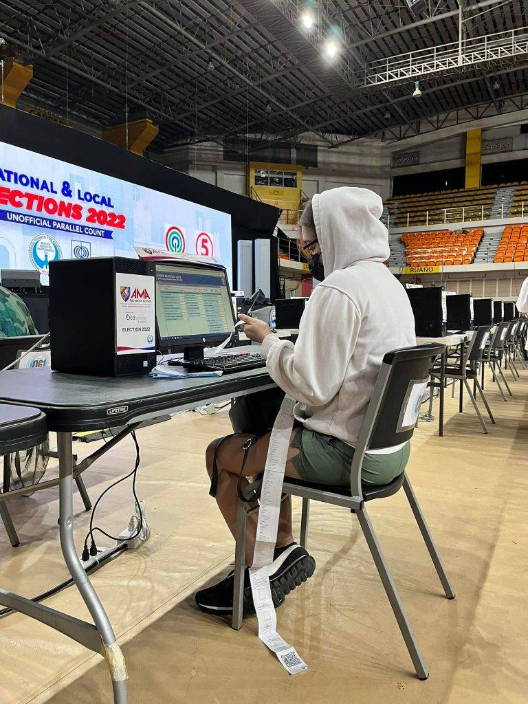 Person in a white hood in front of a computer