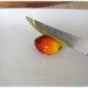 Yellow oil from palm fruit being cut by a knife