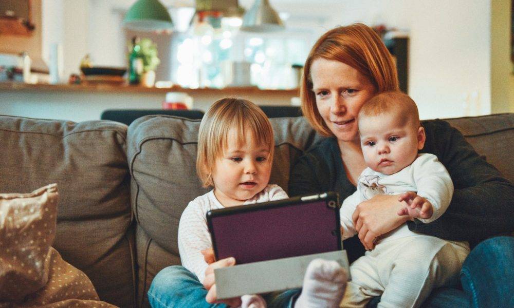 Mom holding two kids and a tablet