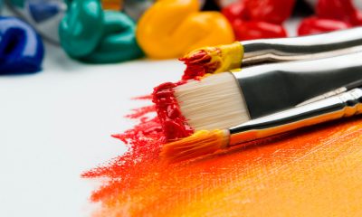 Paintbrushes with red and yellow paint on canvas