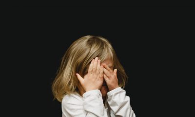 Child covering their face on a black background