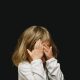 Child covering their face on a black background