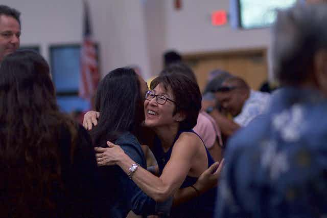 Woman with glasses hugging another woman