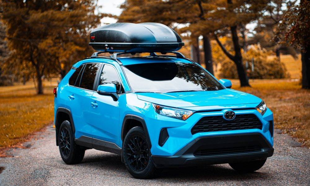 blue suv on the road with tress in the background