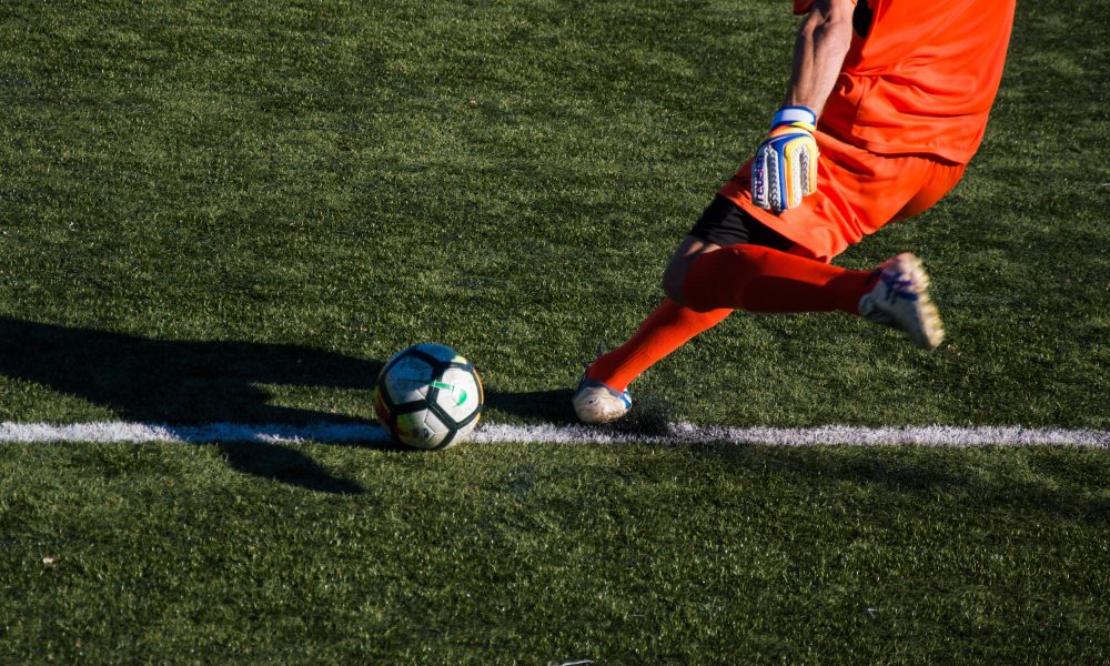 man kicking soccer ball on field