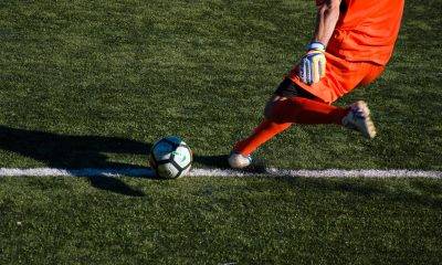 man kicking soccer ball on field