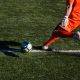 man kicking soccer ball on field