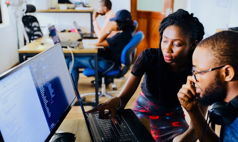 Two people in front of a monitor in an office