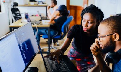 Two people in front of a monitor in an office