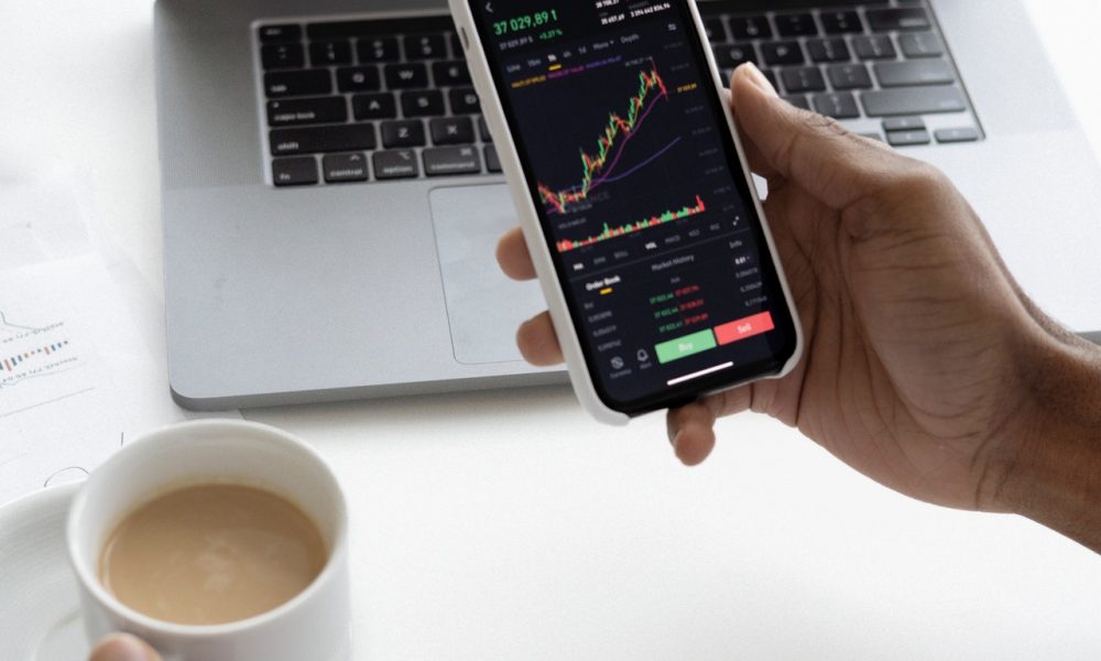 person holding a phone with a laptop