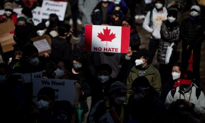 A person holds a Canadian flag sign with the words "no hate"