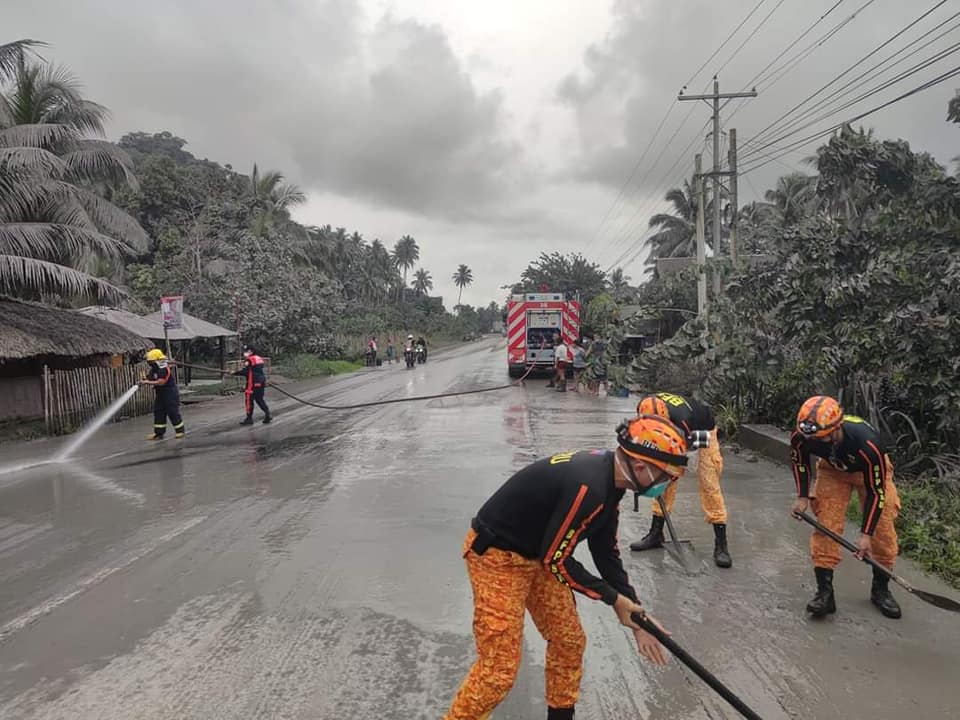 Firemen sweeping volcanic ash on road
