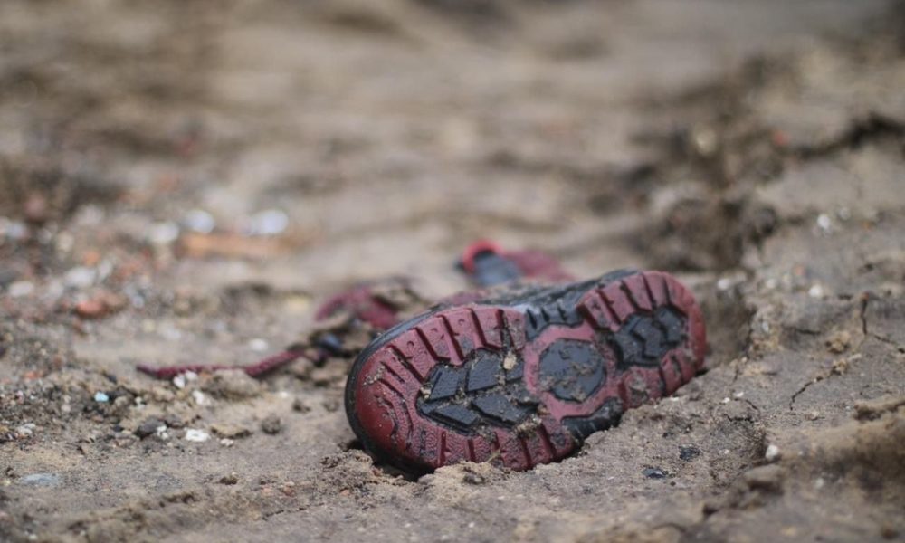 A child's shoe covered by mud